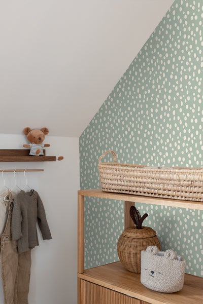 Kinderzimmer mit gemusterter Tapete, Holzregal, Kleidung und Spielzeug