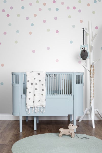 Kinderzimmer mit Gitterbett, Decke und Holzspielzeug