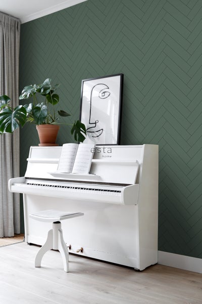 Innenraum mit einem weißen Klavier, einem Hocker, einer Zimmerpflanze und einer Wand mit Fischgrätmuster