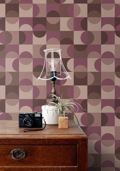 Schlafzimmer mit Bett, Nachttischlampe und Tapete mit geometrischem Muster