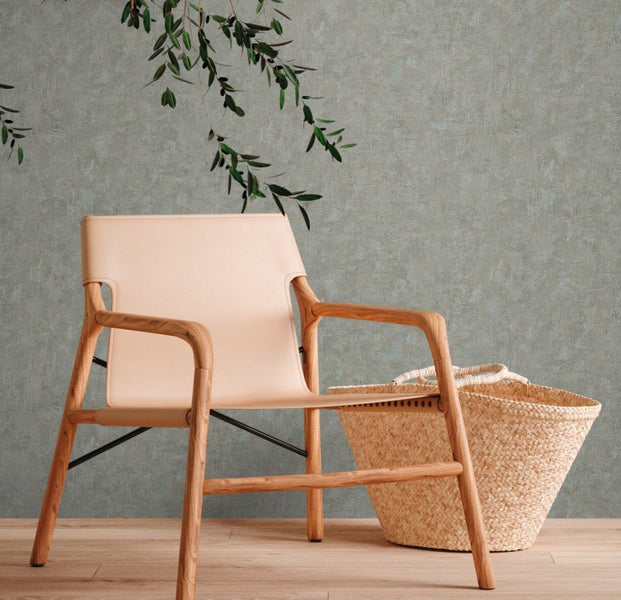 Innenraum mit einem Sessel mit Holzrahmen und einem geflochtenen Korb