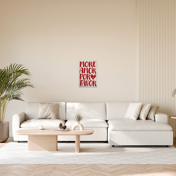 Wohnzimmer mit Poster mit dem Schriftzug 'Mehr Liebe bitte' über einem modularen Sofa.