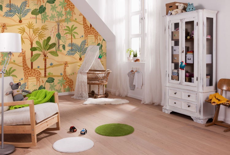 Kinderzimmer mit Giraffentapete, Babybett, Sessel und antikem Schrank