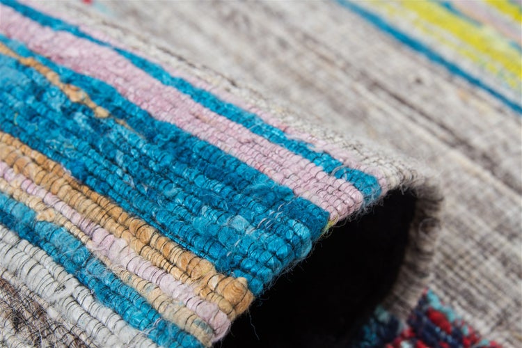 Nahaufnahme eines bunten, gewebten Teppichs mit Streifenmuster und grober Textur.