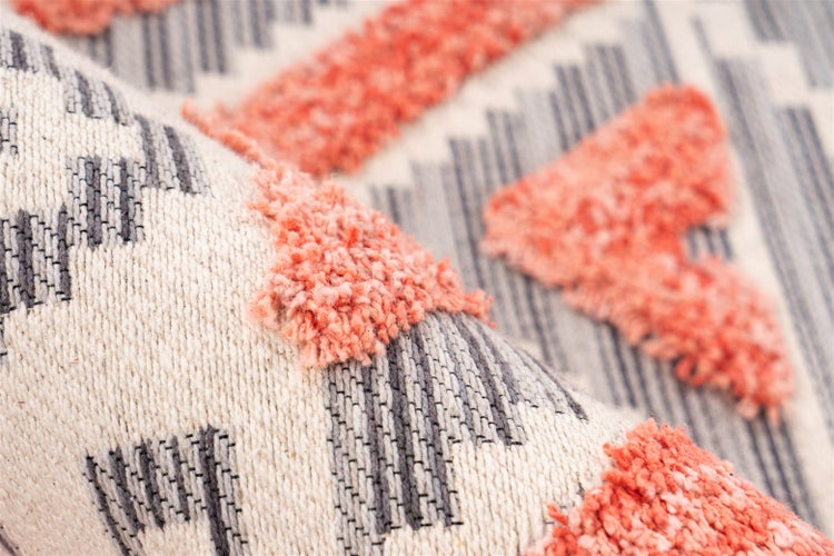 Detailaufnahme eines Teppichs mit Flachgewebe, geometrischem Linienmuster und weichen, erhöhten Tufting-Elementen.