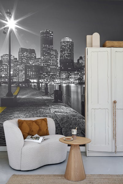 Wohnzimmer mit Sessel, Beistelltisch, Schrank und Fototapete einer nächtlichen Stadtansicht