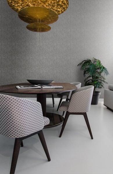 Esszimmer mit rundem Holztisch, Stühlen mit Musterbezug und goldfarbener Hängeleuchte