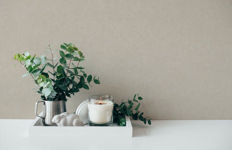 Dekorative Szene mit Kerze, Eukalyptus und Hasenfigur auf einem weißen Tablett.