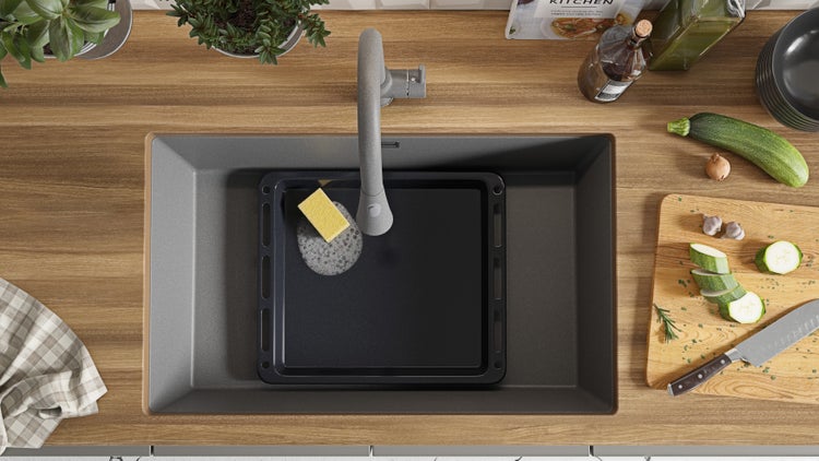 Spüle mit Backblech, Spülschwamm und Armatur in einer Küchenszene