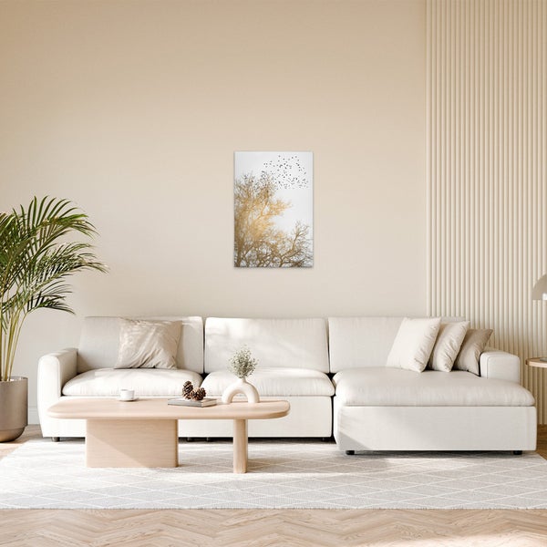Wohnzimmer mit Sofa, Tisch und Wandbild mit Baum und Vogelschwarm