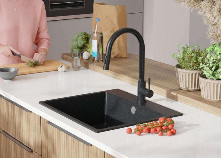 Schwarze Küchenspüle mit Armatur auf einer Küchentheke mit Lebensmitteln