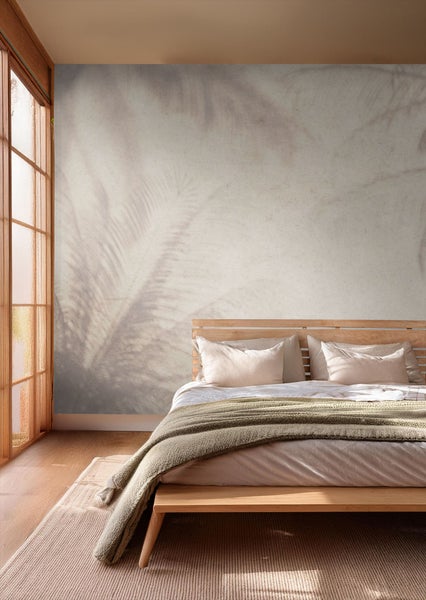 Helles Schlafzimmer mit Holzbett und Wandtapete mit Blättermotiv