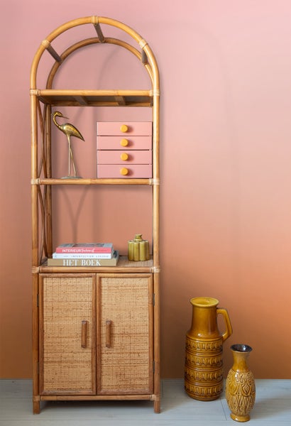 Regal aus Rattan mit Dekoartikeln wie Vasen und einer goldenen Vogel-Skulptur