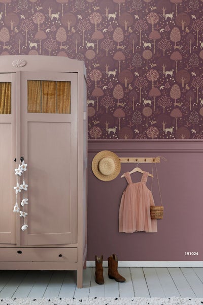 Kind in einem Zimmer mit Waldmotiv-Tapete, die Bäume, Hunde und Vögel zeigt, über einer Wandvertäfelung und Holzboden.