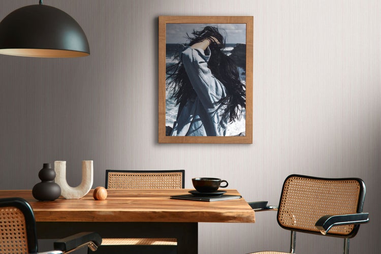 Dekorative Vasen und Bücher auf einem Schrank mit Rattantüren vor einer Tapetenwand