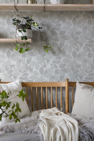 Badezimmerausstattung mit Regal, Seifenspender, Bürste, Schwamm, Seife, Kosmetikpinsel, Zahnbürste, Duftkerze, Toilettenbürstengarnitur und Handtüchern in einem hellen Badezimmer.