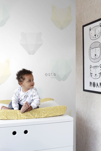 Ein Baby sitzt auf einer gelb gemusterten Wickelauflage auf einer weißen Kommode. Im Hintergrund befindet sich eine mit Tiermotiven verzierte Wand und ein gerahmtes Tierposter.