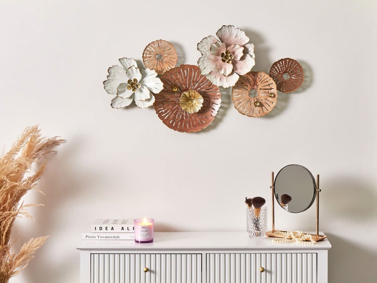 Wanddekoration mit Metallblumen über einem weißen Schrank mit Dekorationsartikeln