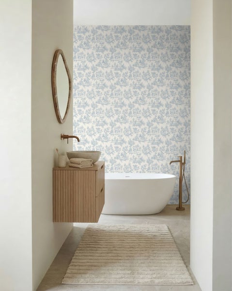 Helles, modern gestaltetes Badezimmer mit Toile-de-Jouy-Mustertapete, freistehender Badewanne, Holzwaschtisch mit Steinwaschbecken und Bronzearmaturen.