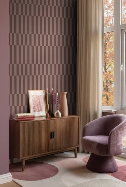 Einrichtungsszene mit Schrank, Sessel, Dekoration und geometrischer Tapete für ein gemütliches Wohnambiente.