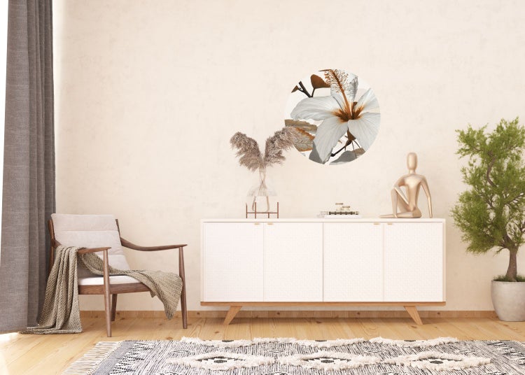 Helles Interieur mit Kommode, Sessel, Pflanze und runder Wanddekoration mit Blütenmotiv.