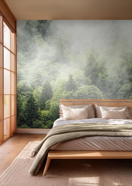 Schlafzimmer mit Fototapete eines nebligen Waldes, Bett mit Decke und Kissen