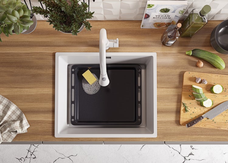 Küchenszene mit Spüle, Armatur, Backblech, Gemüseschneidebrett und Kochbuch.