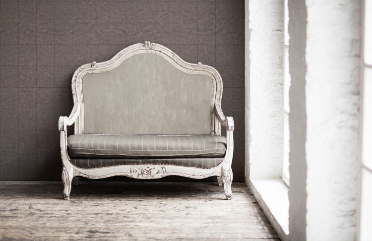 Dekoratives Sofa im Vintage-Stil vor einer gemusterten Wand