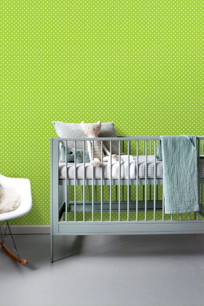 Babyzimmer mit Kinderbett, Spielzeug und gepunkteter Tapete