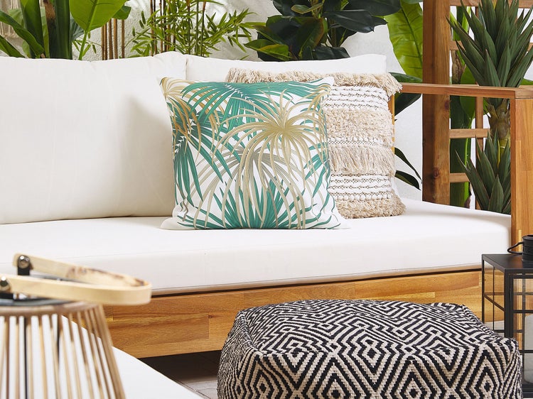 Szene mit Gartenlounge, Kissen mit Blattmuster und Pouf mit geometrischem Muster.