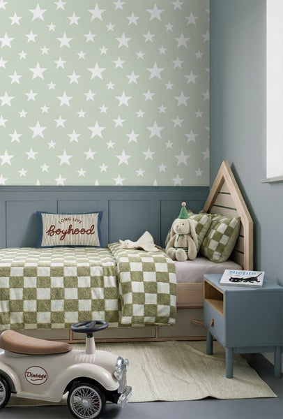 Kinderzimmer mit Sternentapete, blauer Wandvertäfelung, Hausbett aus Holz und grün-weiß karierter Bettwäsche.