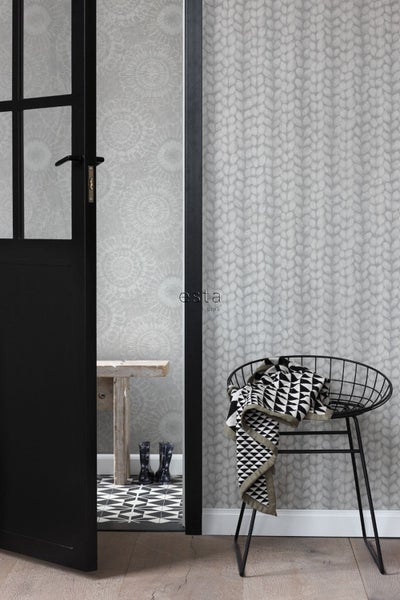 Raumansicht mit Tapeten mit floralen und Strickmustern, Stuhl mit Decke und geöffneter Tür