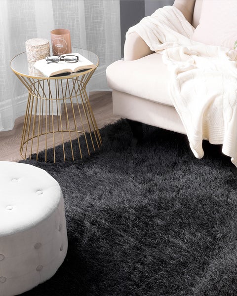 Wohnzimmer mit schwarzem Teppich, Beistelltisch und Ottomane