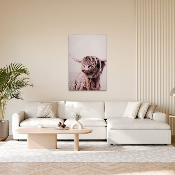 Wohnzimmer mit Sofa, Couchtisch und Wandbild eines Hochlandrindes