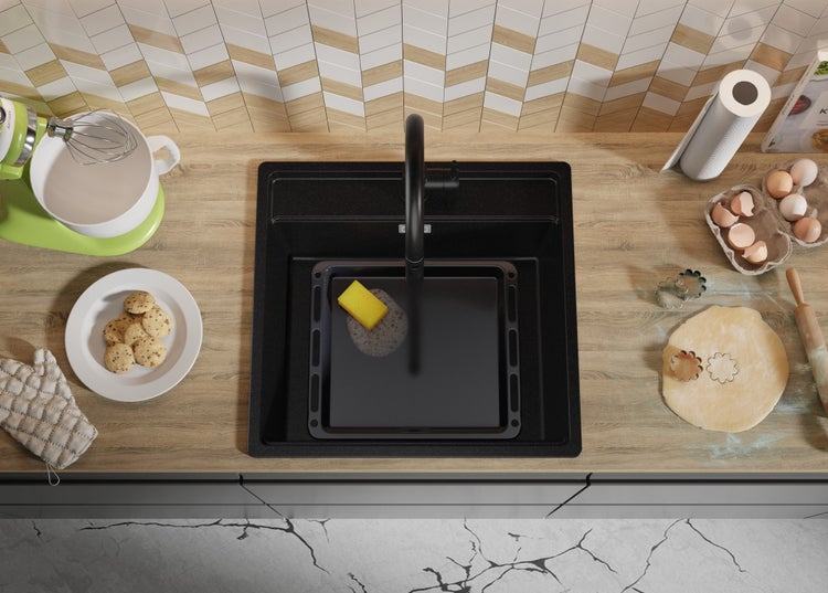 Küchenspüle mit Armatur, Backblech und Küchenutensilien auf einer Arbeitsplatte.