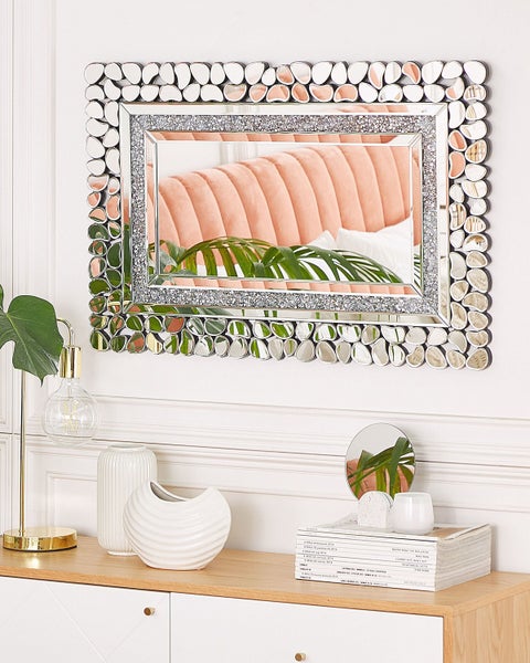 Dekorativer Spiegel mit Schmucksteinen an der Wand über einem Sideboard