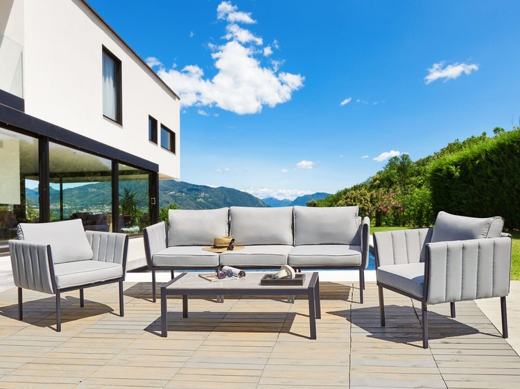 Gartenmöbelset mit Sofa, Sesseln und Tisch auf einer Terrasse vor einem modernen Haus