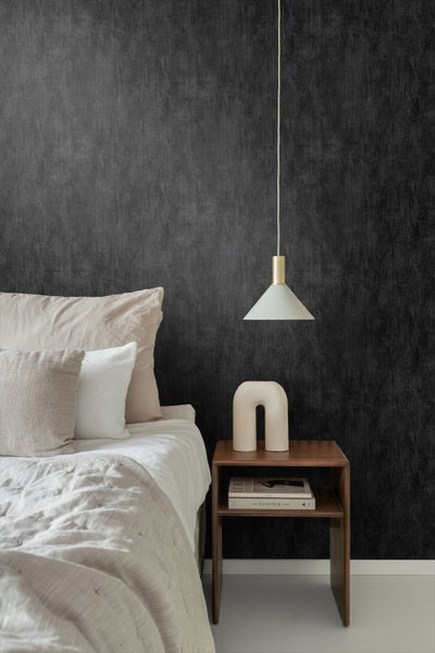 Schlafzimmer mit Bett, Nachttisch und strukturierten Tapeten