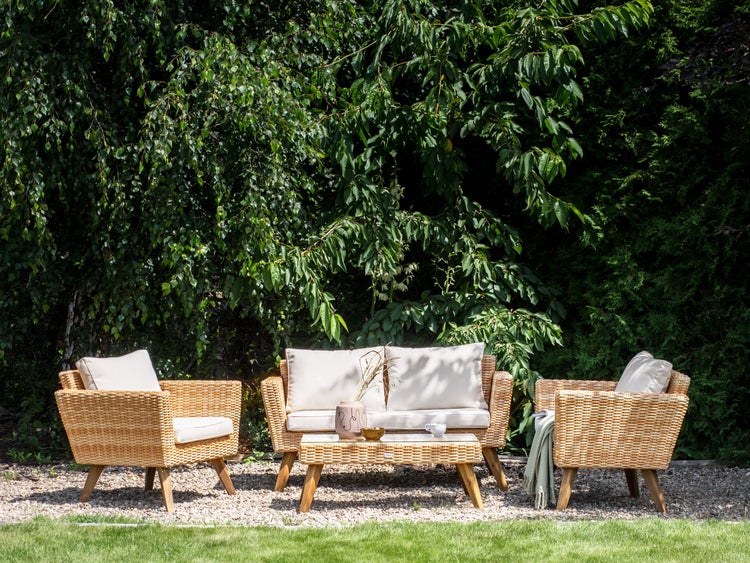 Gartenmöbel-Set mit Korbsesseln, Sofa und Tisch vor grünem Hintergrund