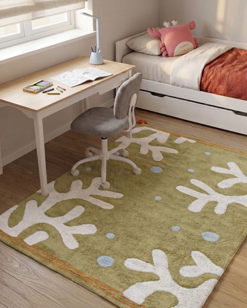 Ein Kinderzimmer mit Schreibtisch, Stuhl und einem Teppich mit Schneeflockenmuster auf einem Holzboden.