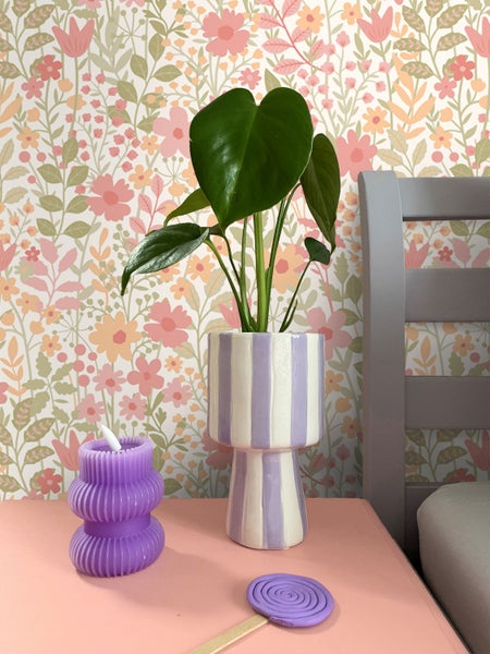 Dekorative Szene mit Topfpflanze, Kerze und floraler Tapete