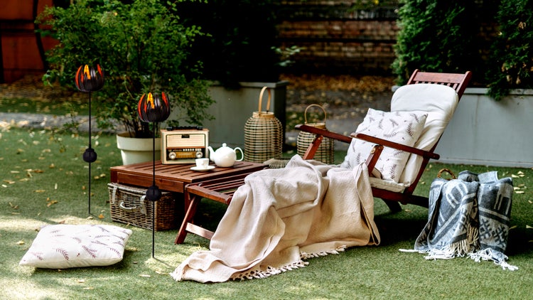 Gartenarrangement mit Liegestuhl, Beistelltisch, Laternen und Dekoration auf Rasen