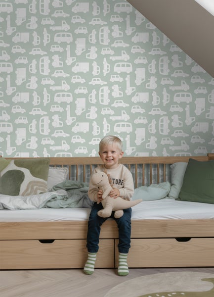 Vliestapete mit Automuster in Grün und Weiß in einem hellen Kinderzimmer mit einem Holzbett.