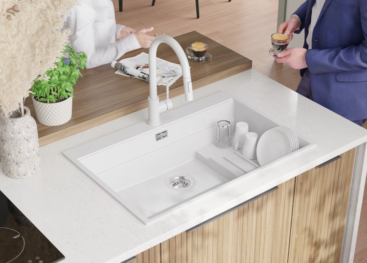 Küchenspüle mit Abtropffläche, Armatur und Geschirr auf einer Küchentheke mit Personen im Hintergrund