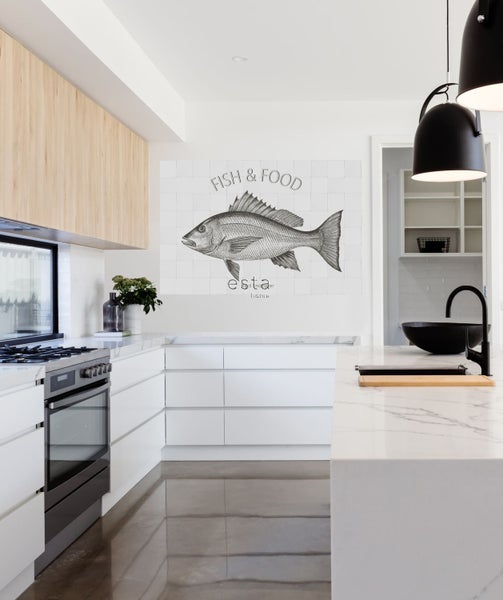Helle Küche mit Küchenschränken, Herd, Spüle und Wanddekoration mit Fischmotiv