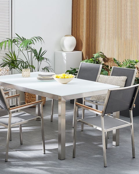 Gartenszene mit Esstisch aus Metall und Glas sowie passenden Stühlen mit Textilbespannung