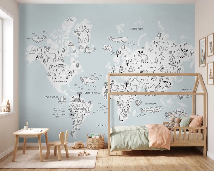 Fototapete mit Weltkarte und Tierzeichnungen in einem hellen Kinderzimmer mit Holzmöbeln und einem Hausbett.
