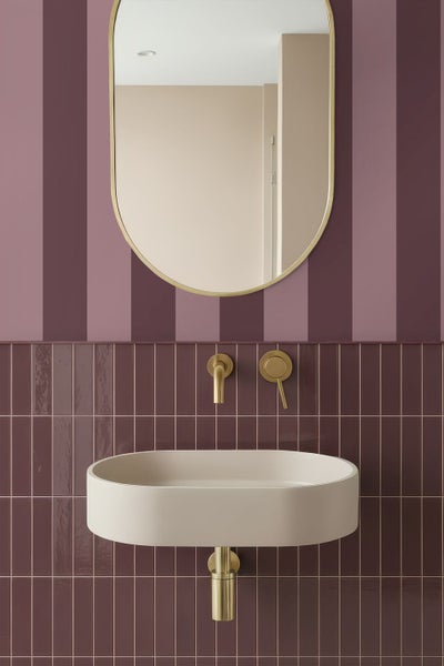 Modernes Badezimmer mit beige-farbenem Aufsatzwaschbecken, goldener Wandarmatur, Wandspiegel, gestreifter Tapete und vertikalen schmalen Wandfliesen.