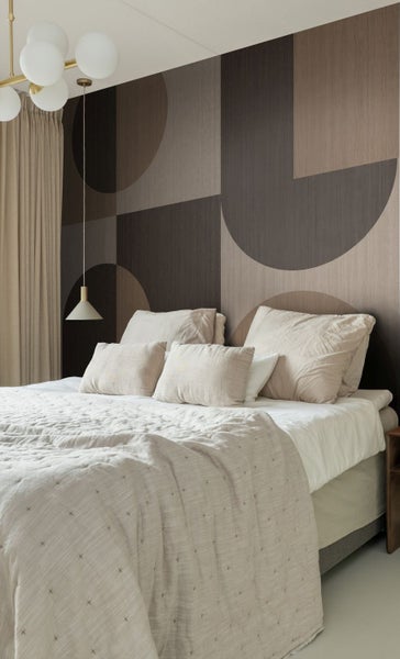 Schlafzimmer mit Bett, geometrischer Tapete und Pendelleuchte