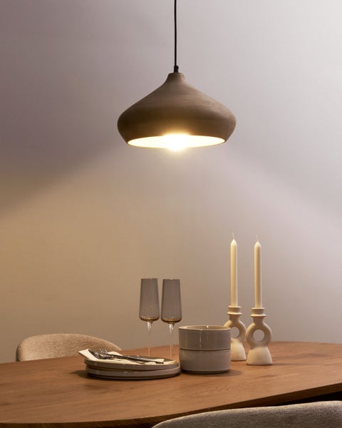 Esstisch mit Geschirr, Gläsern, Kerzenständern und hängender Leuchte für stimmungsvolle Beleuchtung.